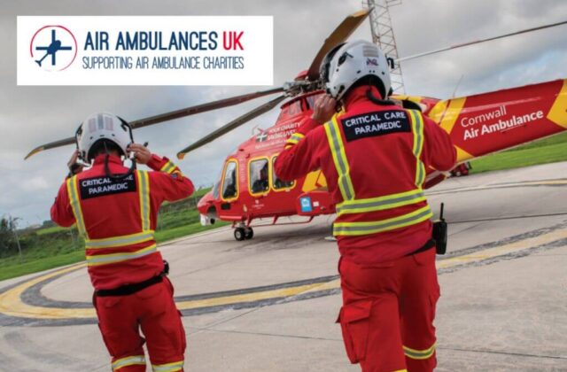 two air ambulance crew walking towards the helicopter in uniform with the logo Air Ambulances UK